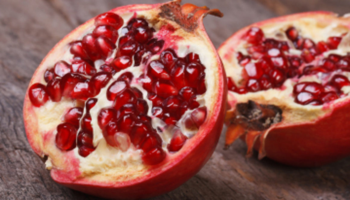 Cut Ripe Pomegranate On An Old Wooden Table. Horizontally