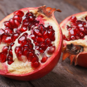 Cut Ripe Pomegranate On An Old Wooden Table. Horizontally