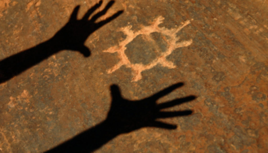 Shadow Of Hands Worshipping Sun Petroglyph Carved Into Sandstone