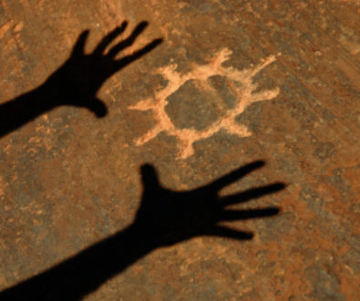 Shadow Of Hands Worshipping Sun Petroglyph Carved Into Sandstone